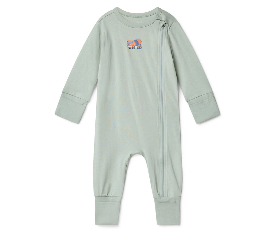 Egy világoszöld baba rugdalózó narancssárga betonkeverő mintával a mellkasán fehér háttér előtt fekszik.