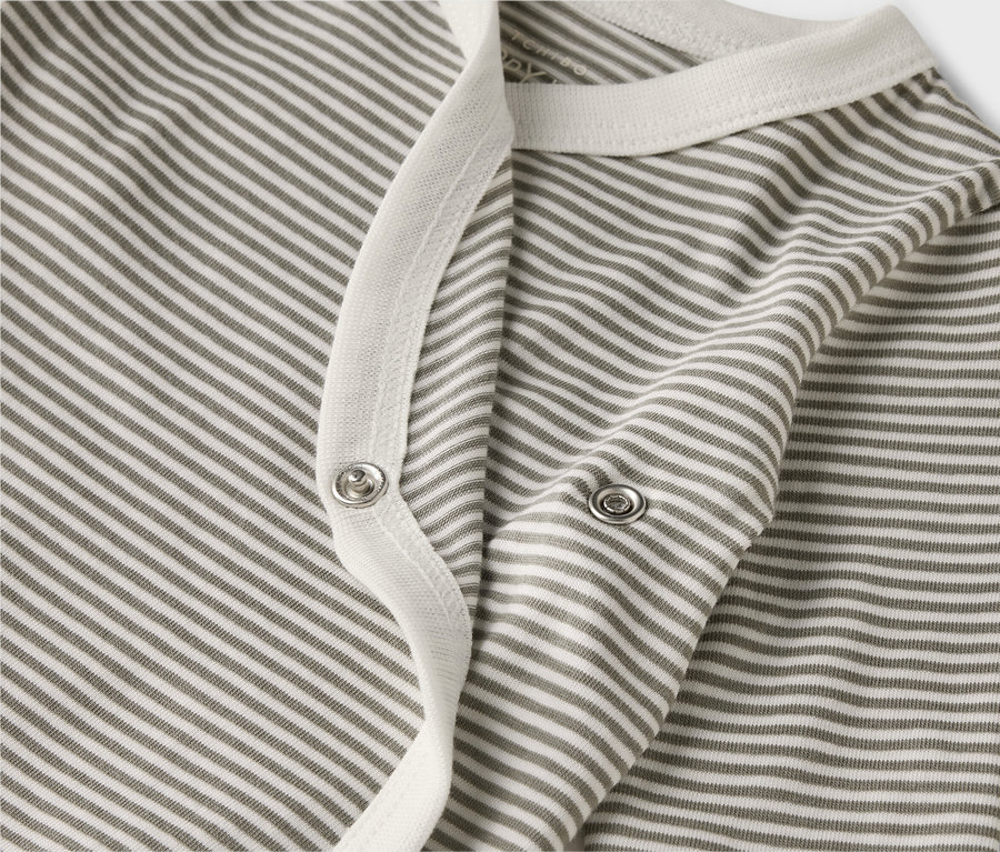 Közeli kép egy csíkos, hosszú ujjú babaruháról, patentokkal.