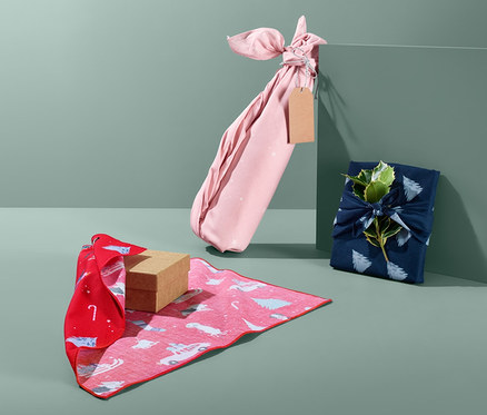 Három ajándék különböző színű, 3 karácsonyi textil csomagolóanyagba csomagolva.