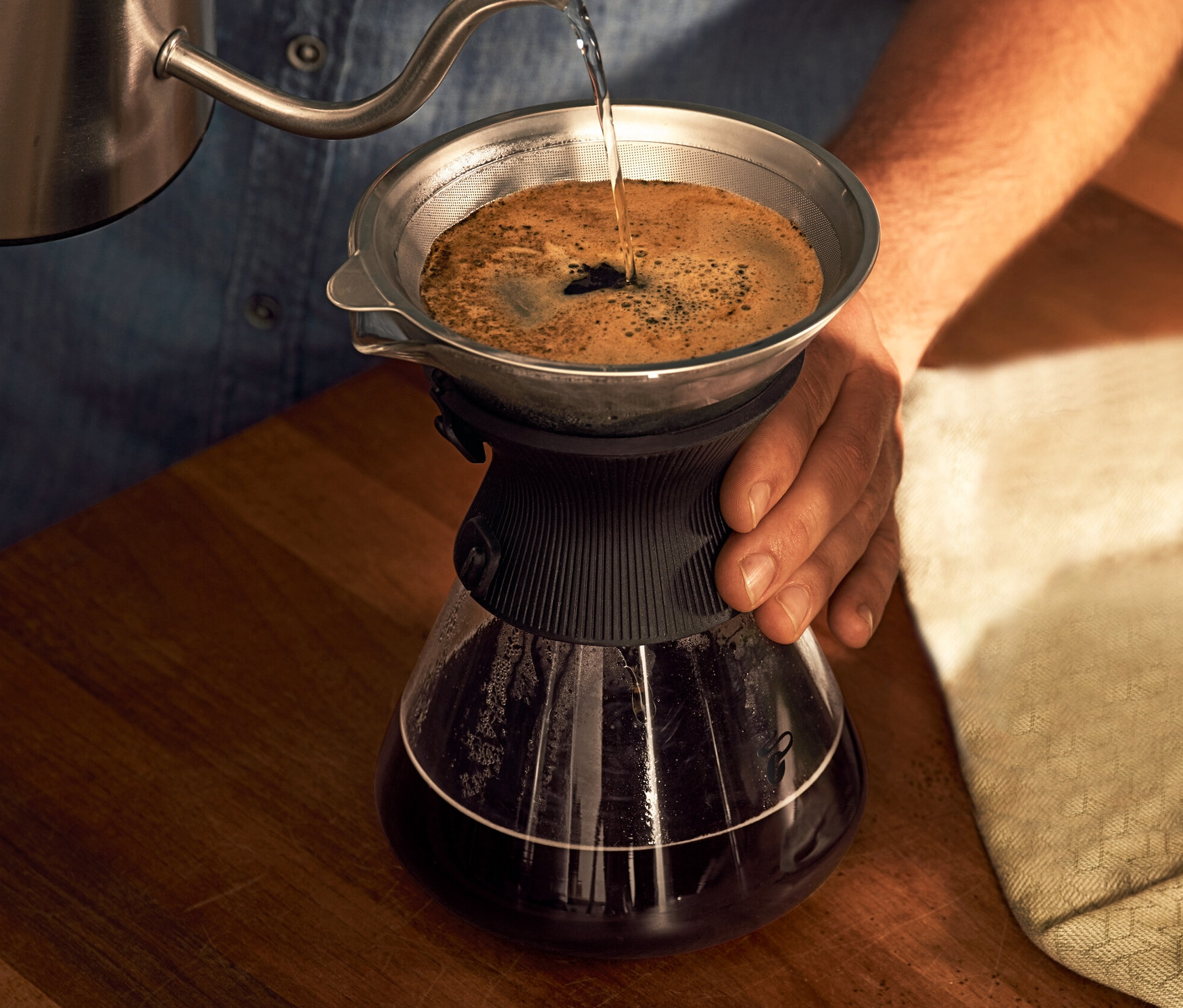 Férfi vizet önt a BEEM Pour Over 0,75 l-es üvegkancsóba, kávészűrővel.