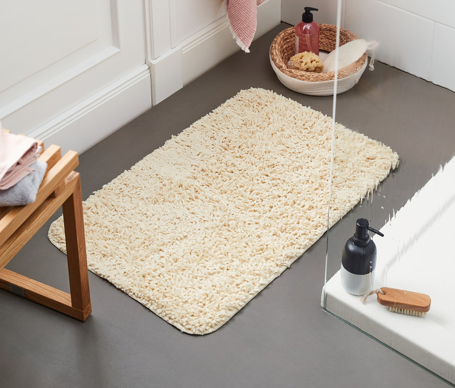 A vanília színű, 50 x 80 cm-es kádkilépő a padlón fekszik.