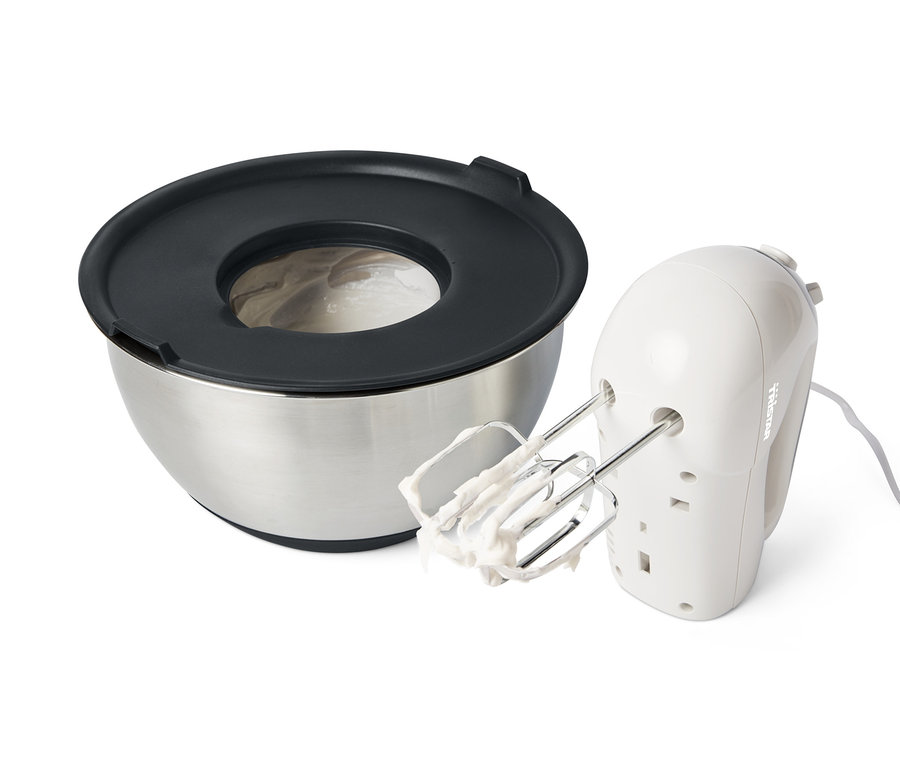 Egy rozsdamentes acél keverőtál fekete fedővel és egy kézi mixer tésztával a habverőkön.