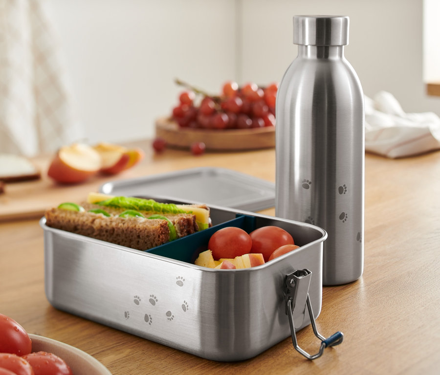 Egy nemesacél ételhordó doboz és kulacs egy fa asztalon.