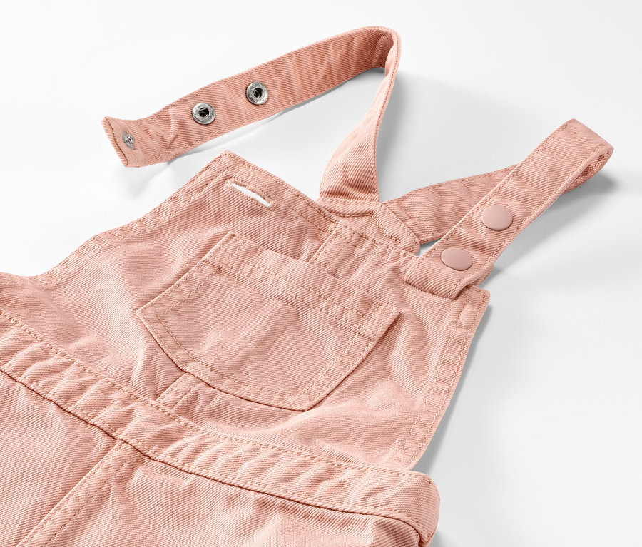 Egy rózsaszín kislány kantáros ruha részlete.