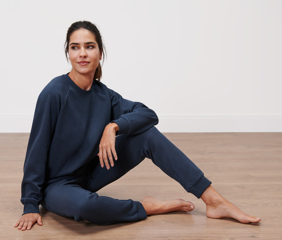 Nő ül a padlón sötétkék női szabadidő szettben.