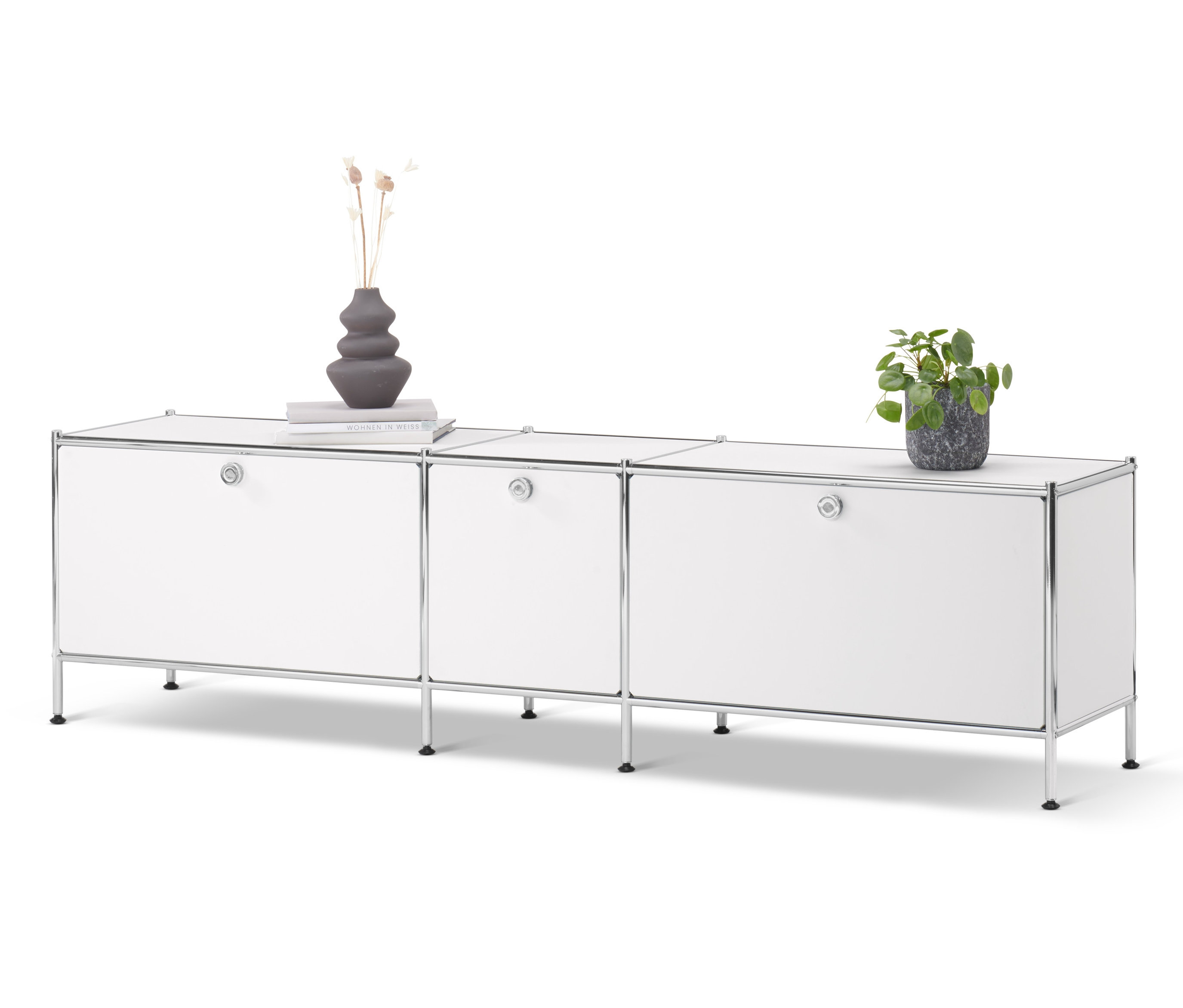 Fehér »CN3« alacsony komód három ajtóval. A komódon váza, könyv és egy cserepes növény található.