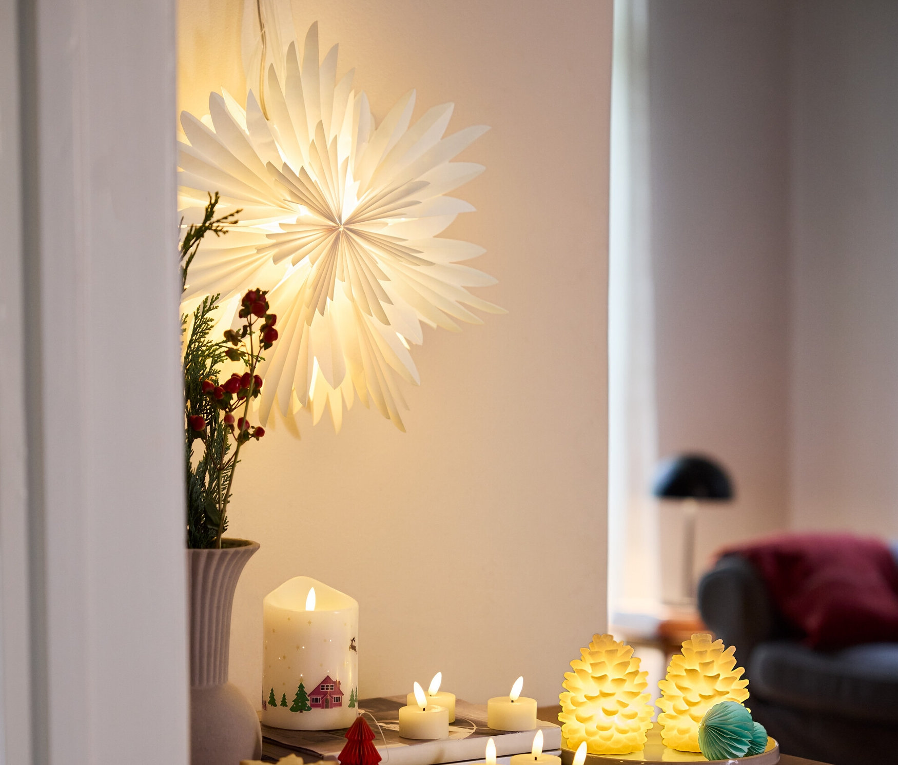 Az asztalon 2 LED-es valódi viasz fenyőtoboz, egy LED-es valódi viaszgyertya, karácsonyi mintával, 6 db LED-es, akkumulátoros valódi viaszgyertya és egy LED-es papírcsillag látható.