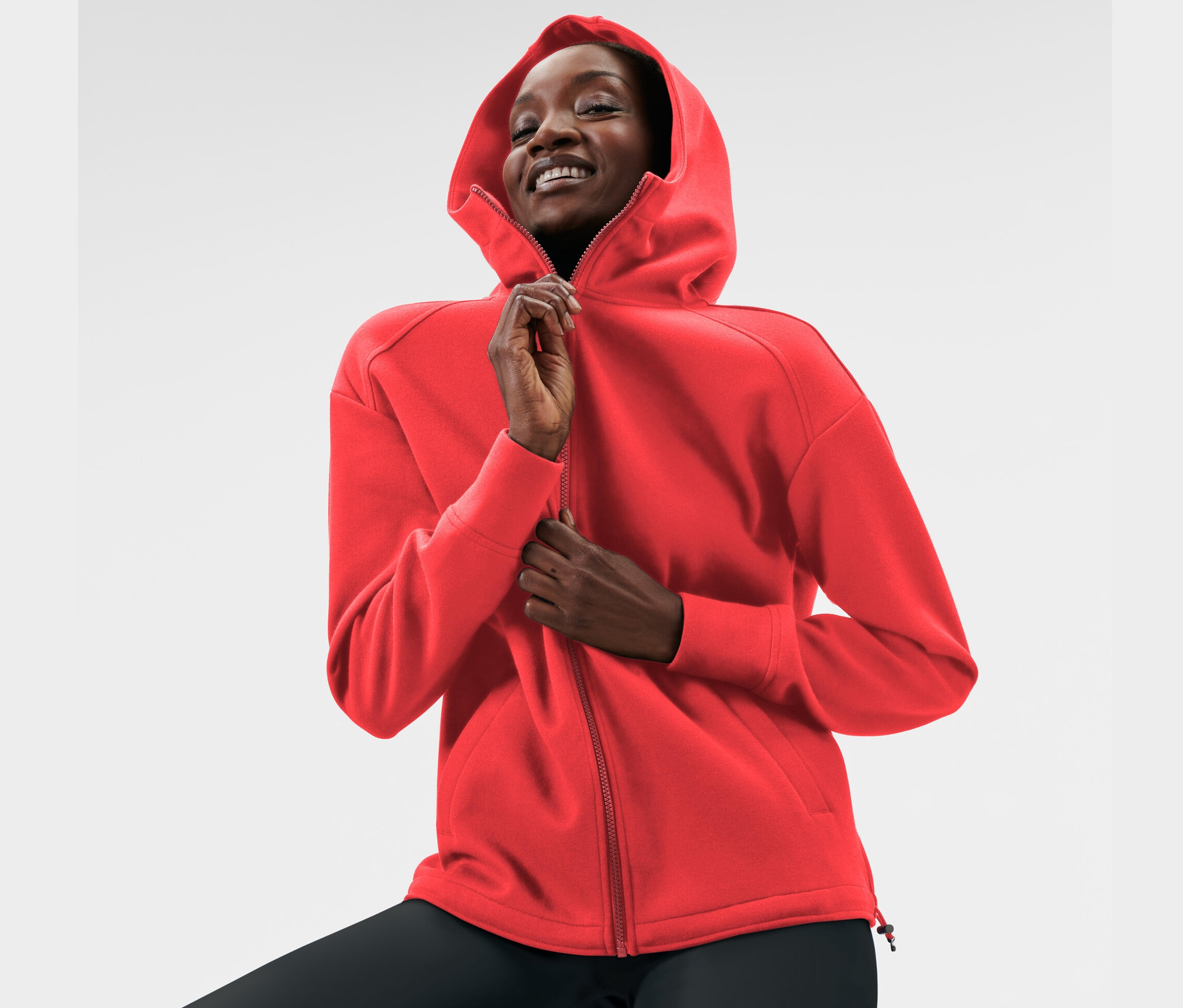 Nő cipzározza a piros kapucnis szabadidőfelsőt.