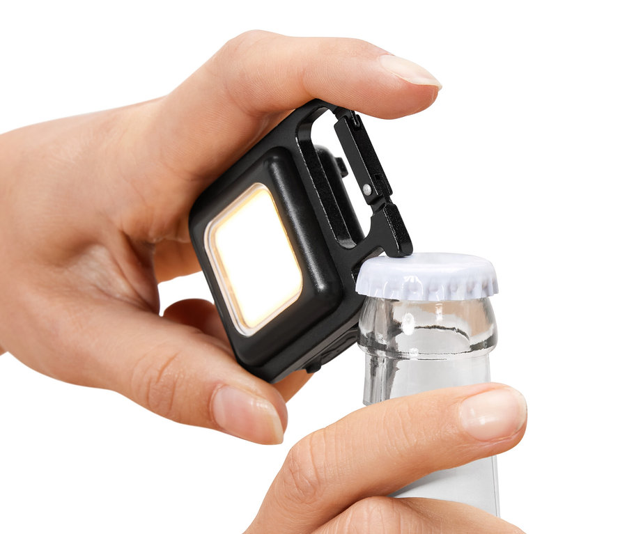 Egy kéz egy multifunkcionális lámpával üveget nyit.