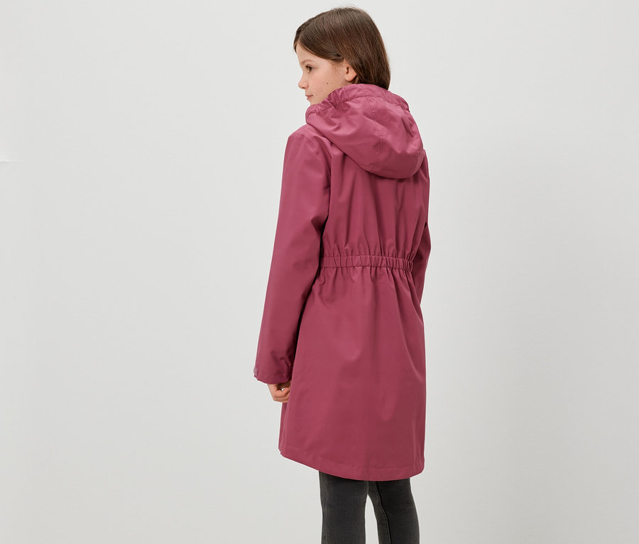 Egy lány háttal áll a kamerának, és egy Kinder-Regenparkát visel.