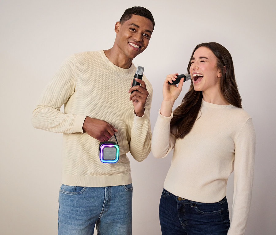 Férfi mikrofont és hangszórót tart, nő énekel a mikrofonba.