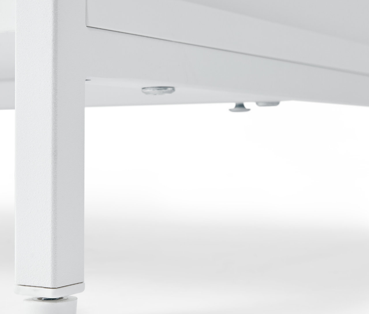 Közelkép egy fehér »KLAAR« komódról 4 fiókkal, alulnézet a lábakra.