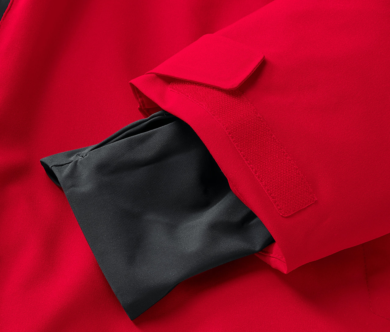 Egy piros kabát részlete, fekete belső zsebbel az ujján.