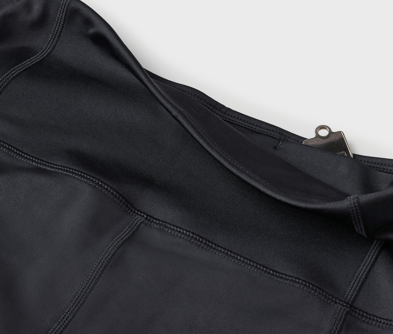 Fekete leggings részlete zsebbel és ezüst színű csíptetővel.