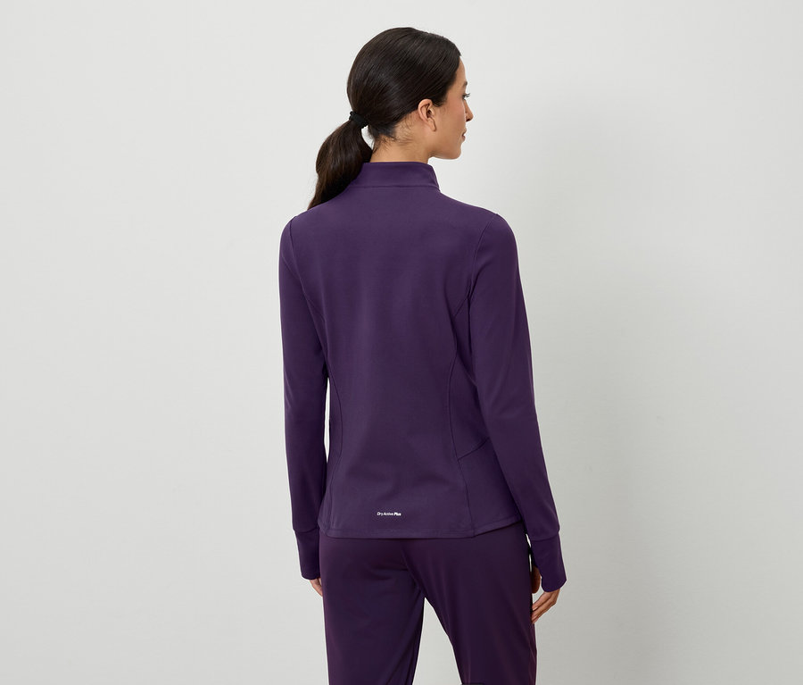 Hátulnézet egy barna hajú, lófarokba kötött nőről, aki lila kabátot és nadrágot visel.