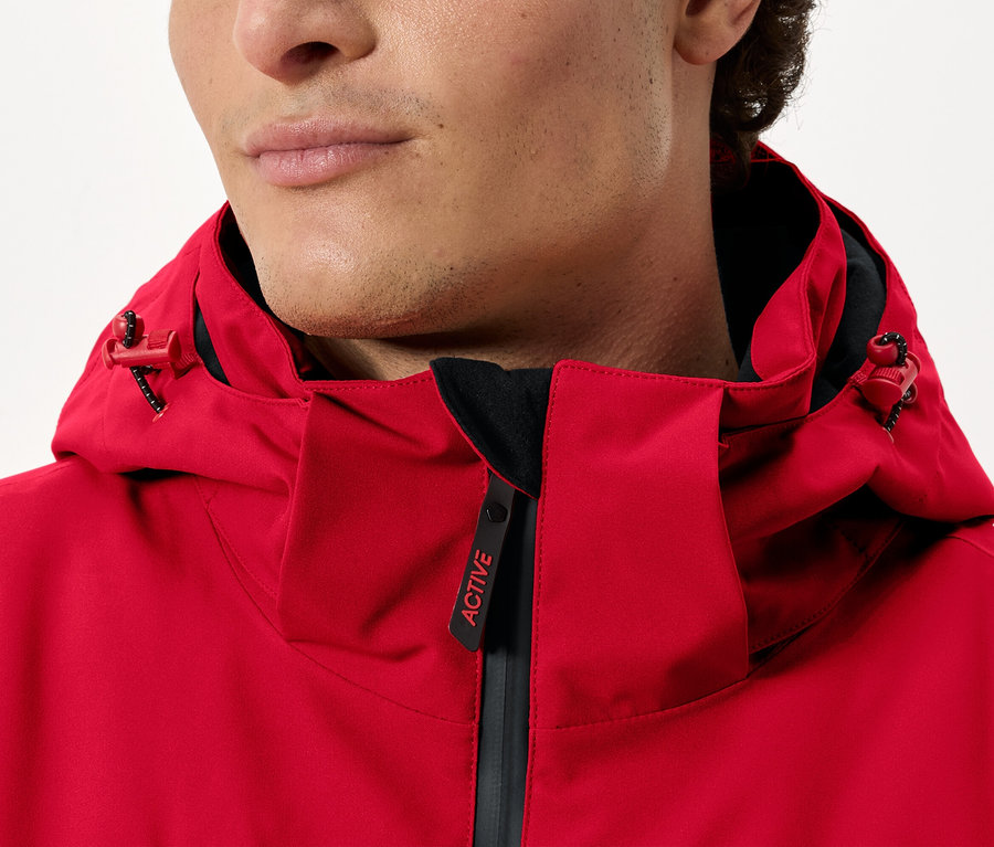 Férfi visel egy piros, kapucnis kabátot.