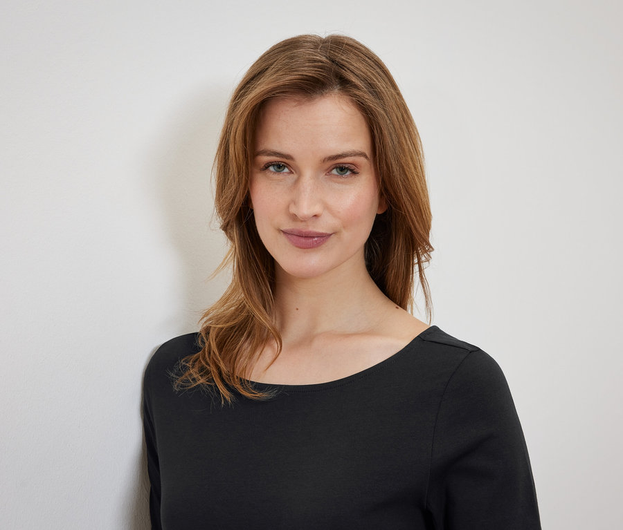 Portré egy barna hajú nőről fekete pólóban.