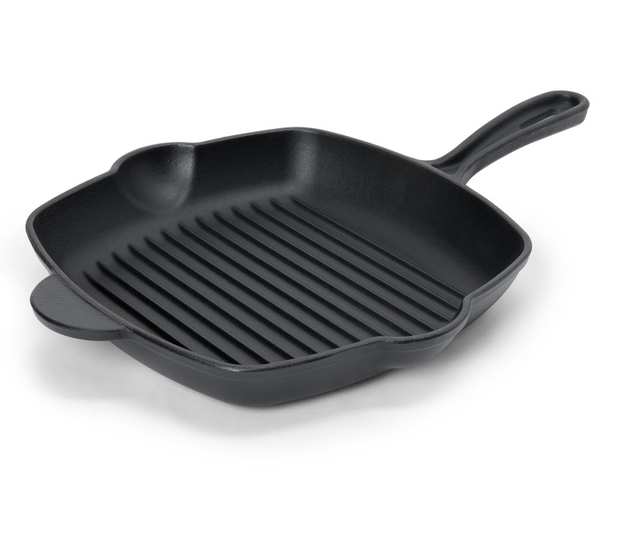 Egy fekete, bordázott grillserpenyő fogantyúval egy fehér felületen.