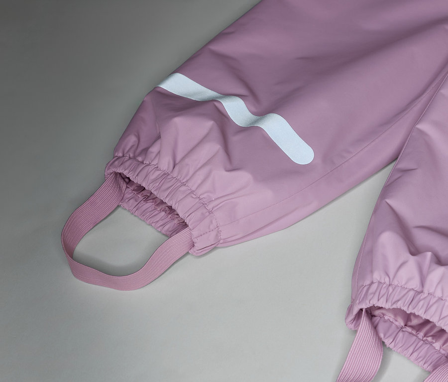 Közelkép rózsaszín esőnadrágról, elasztikus pántokkal és fényvisszaverő csíkokkal a szárakon.