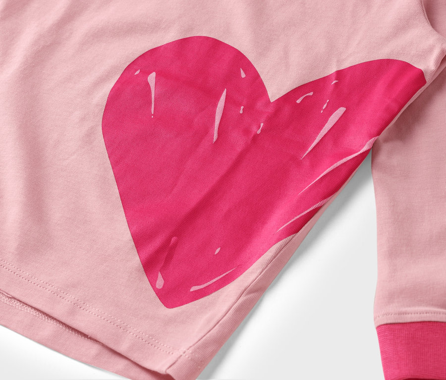 Egy rózsaszín anyag közeli képe, nagy, rózsaszín szívnyomattal.