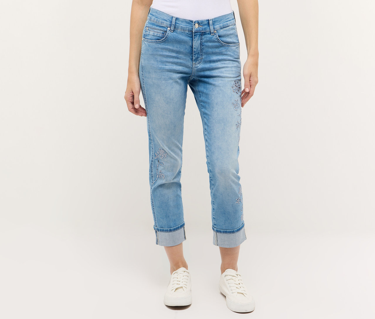 Egy személy Angels denim »Cira Boho« farmert és fehér tornacipőt visel fehér háttér előtt.