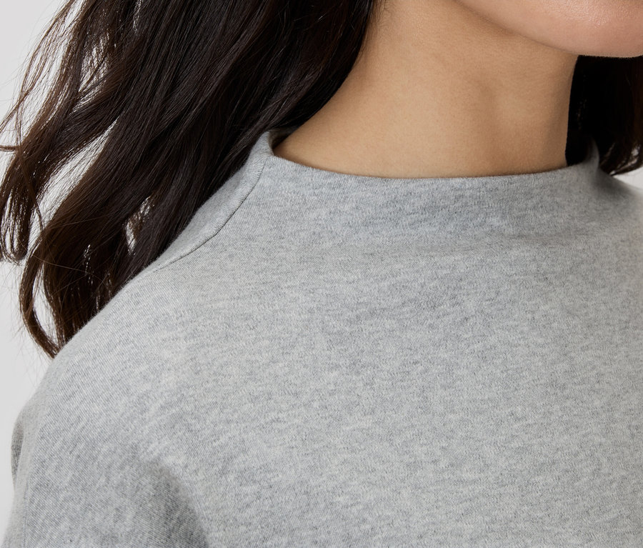 Közelkép egy nőről, aki szürke garbós felsőt visel.