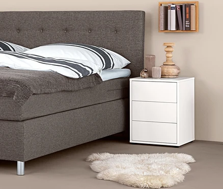 Boxspring ágy boxspring éjjeliszekrénnyel és dekorációkkal.