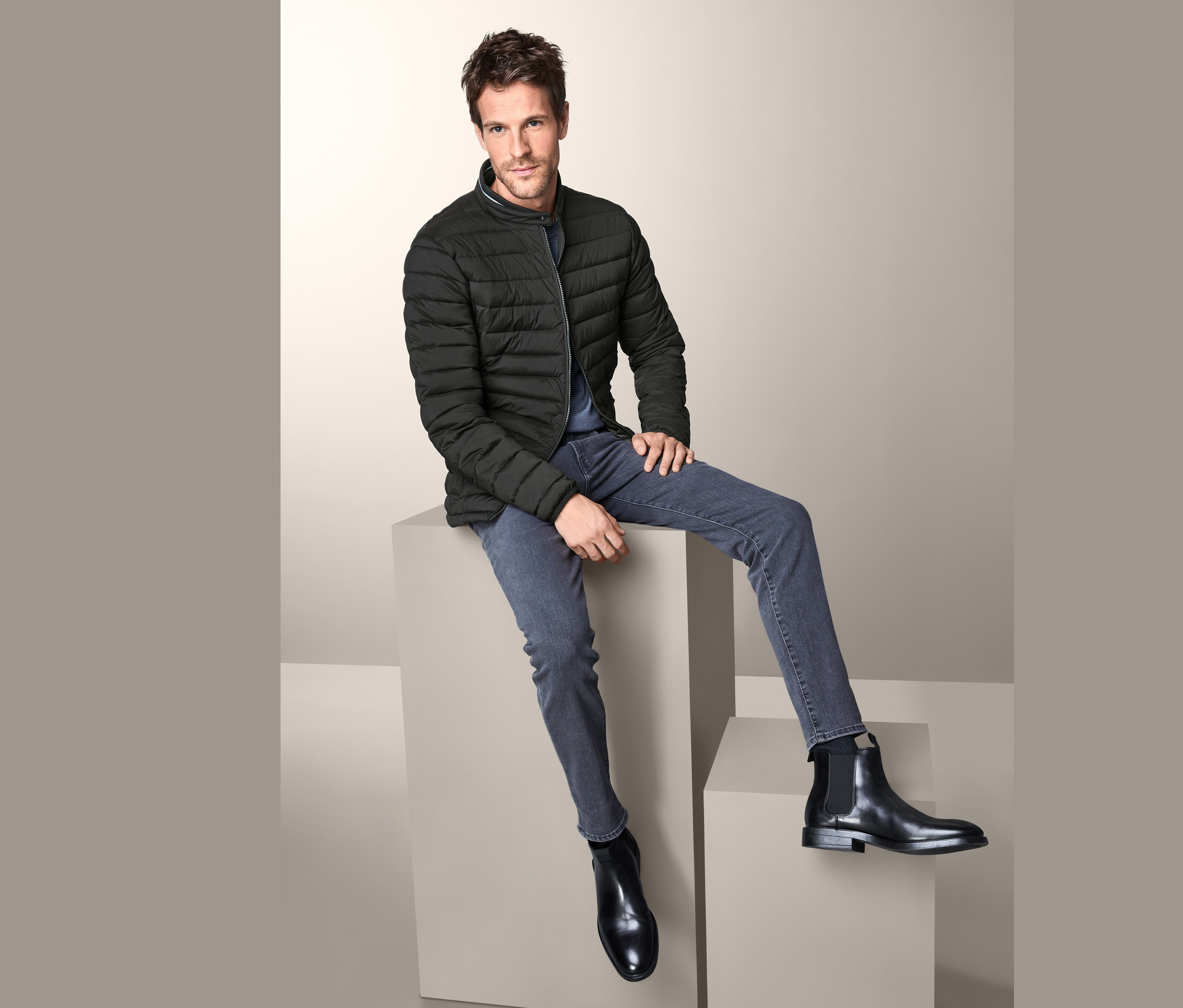 Férfi ül kockákon és steppelt dzsekit visel.