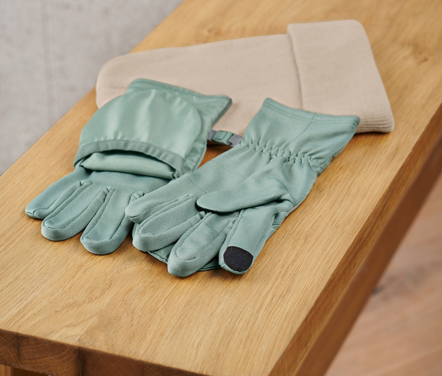 Egy pár 2 az 1-ben zöld futókesztyű zsebbel egy fa padon.