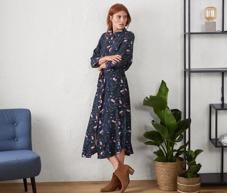 Egy nő virágmintás ingruhában pózol.