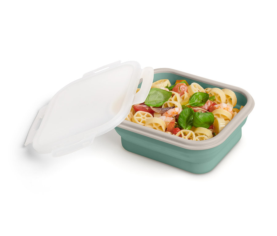 Egy összehajtható ételhordó doboz tésztasalátával, a fedője félig nyitva.