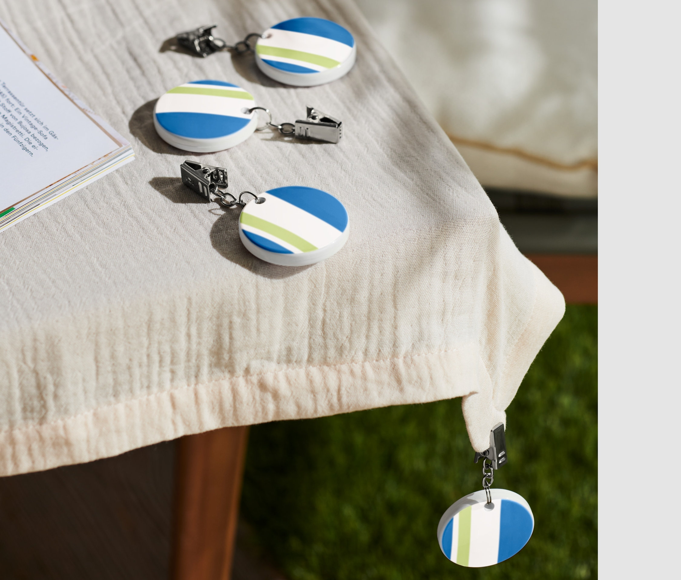 Az asztalon négy asztalterítő-leszorító található egy csésze kávé és egy könyv mellett.