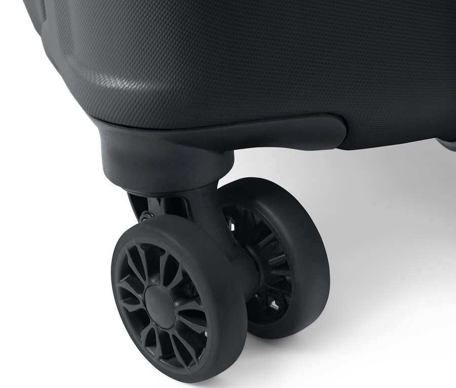 Egy nagyméretű kemény bőrönd részlete, amely a texturált felületet és két fekete kereket mutatja.