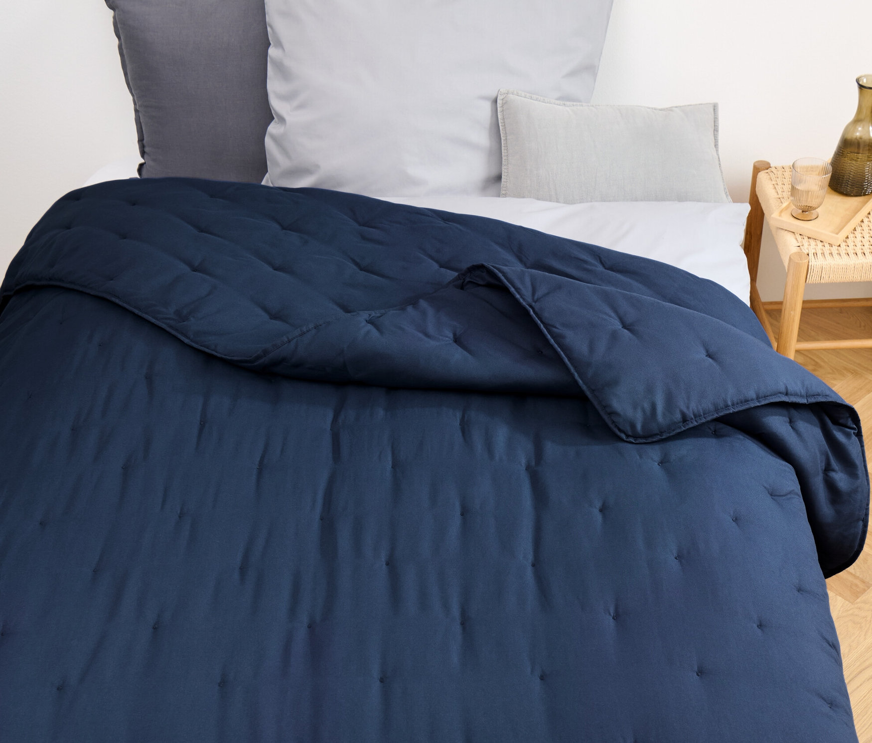 Kék steppelt ágytakaró egy ágyon.