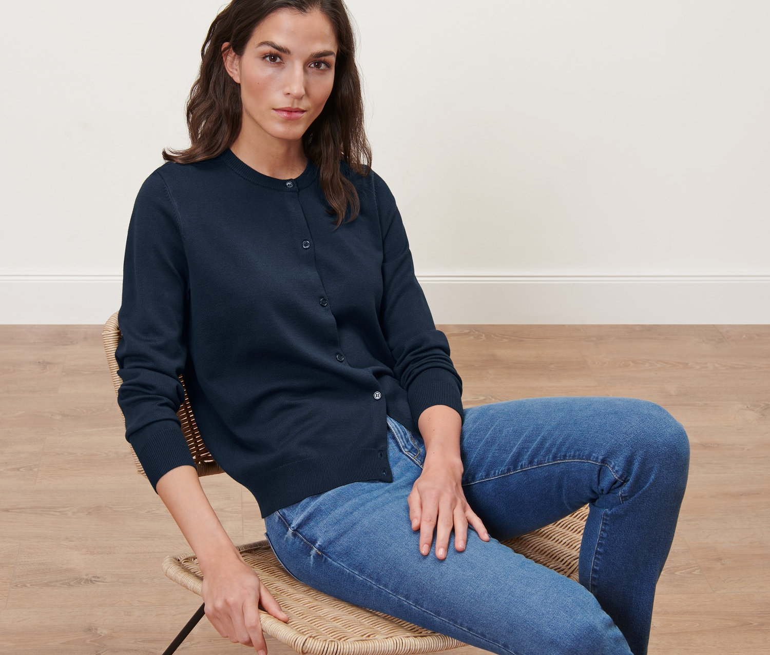 Nő ül egy széken, sötétkék finomkötésű kardigánt visel.