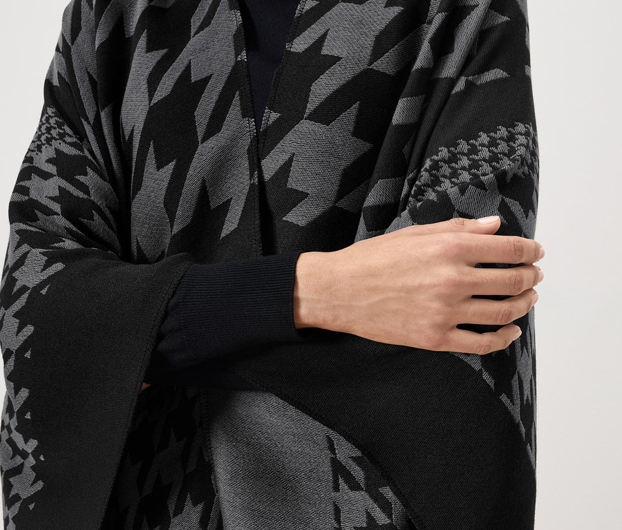 Nő visel fekete-szürke, kakasmintás köpenyt.