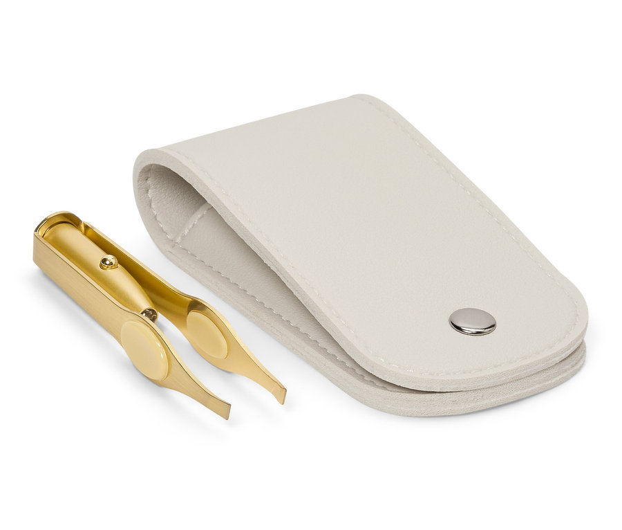 Egy arany színű csipesz egy nyitott, fehér tok mellett fekszik.