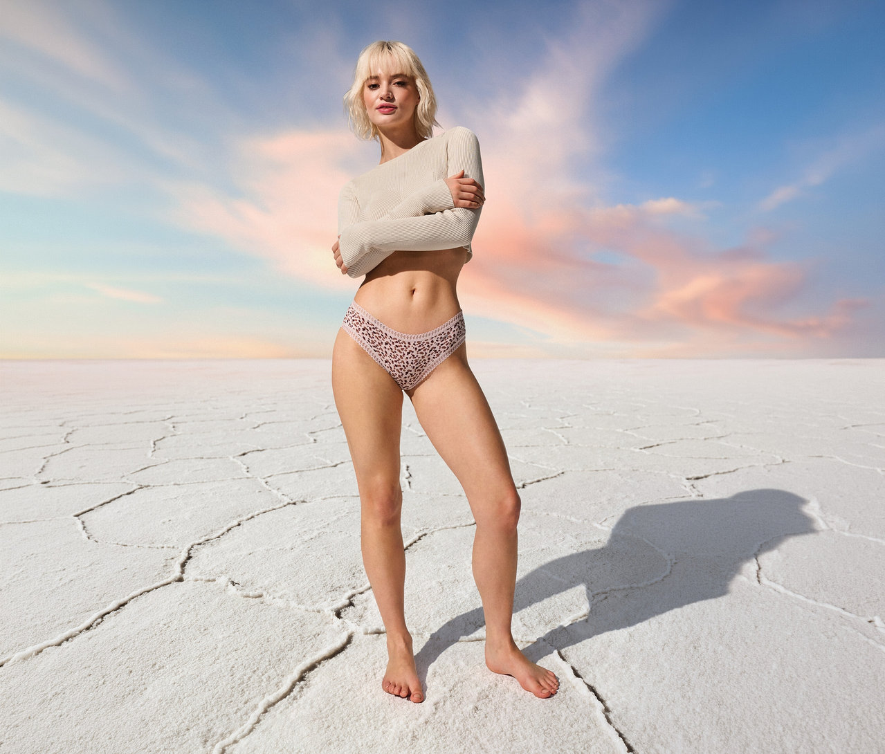 Nő áll mezítláb 3 Sloggi Go Crush hipster alsó, rózsaszín alsóban a kék ég előtt.