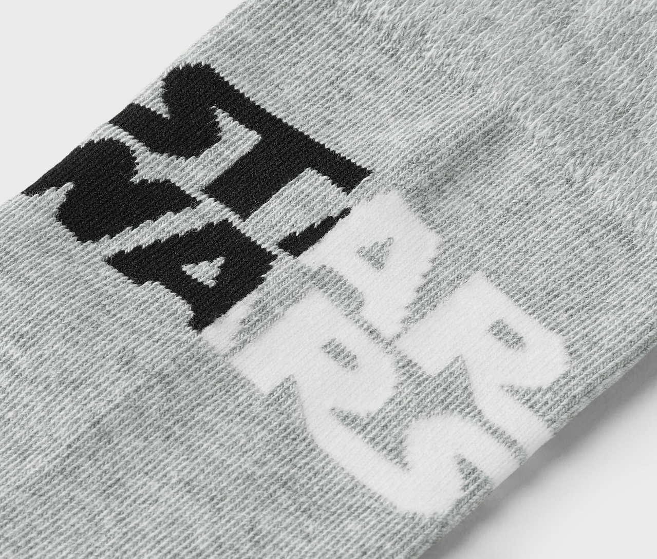 Egy szürke zokni részlete fekete és fehér felirattal.