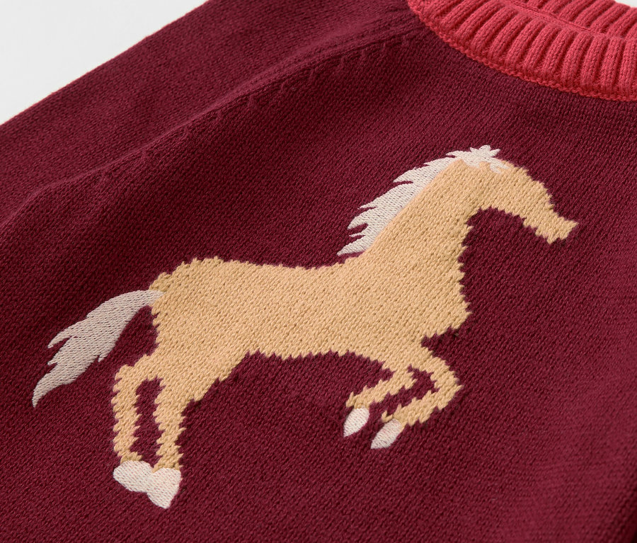 Egy bordó színű Kinder-Strickpullover részletes nézete barna ló mintával.