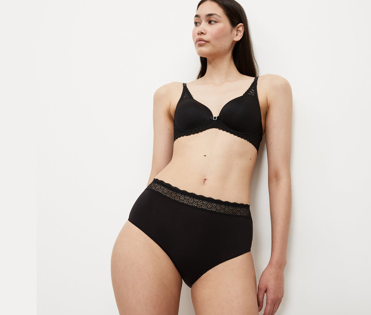 Nő fekete melltartót és alsót visel.