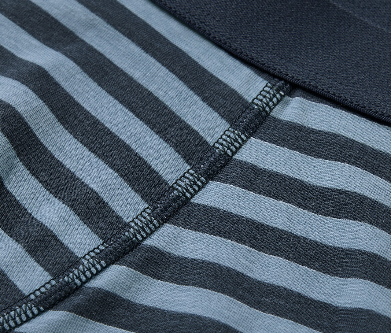 Egy kék-szürke csíkos boxer alsónadrág részlete, sötétkék derékpánttal.