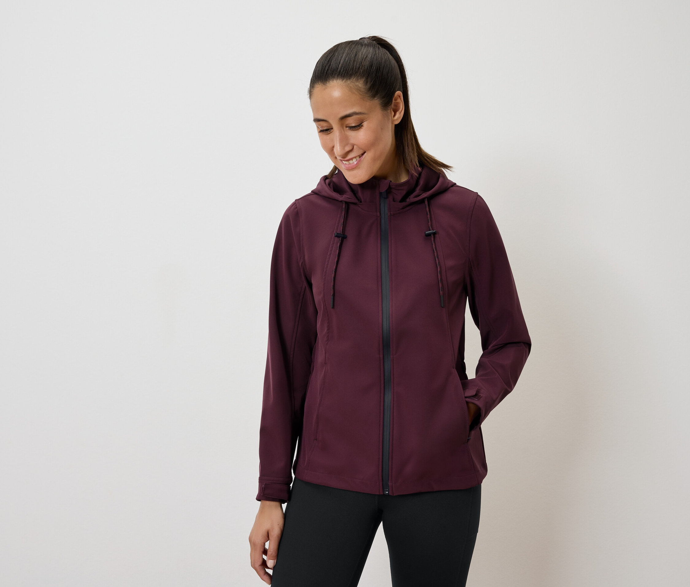 Nő visel bordó kapucnis kabátot és fekete leggingset.