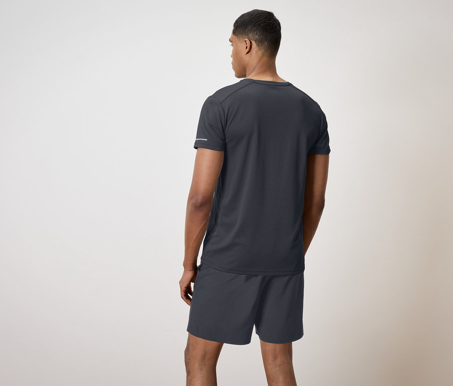 Férfi fekete pólóban és rövidnadrágban áll háttal a nézőnek.