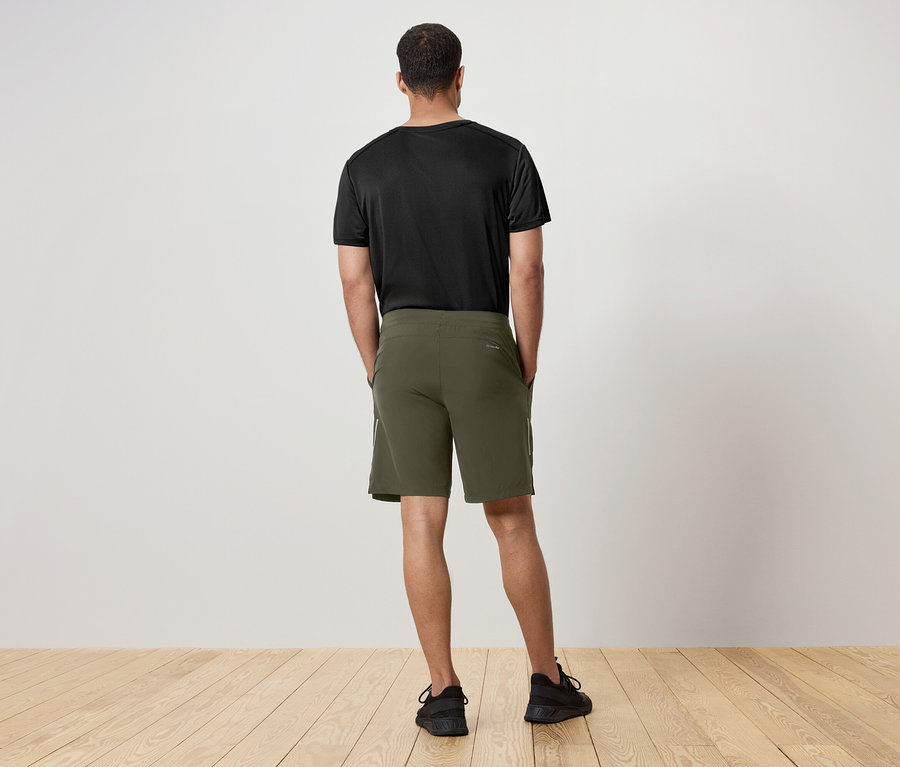 Egy férfi hátulról látható, fekete pólót és zöld rövidnadrágot visel.