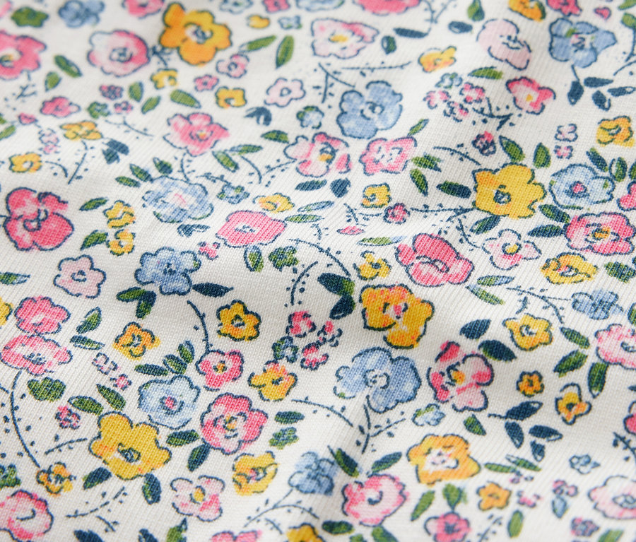 Közelkép egy virágmintás, rózsaszín, kék és sárga színű gyermek leggingsről.