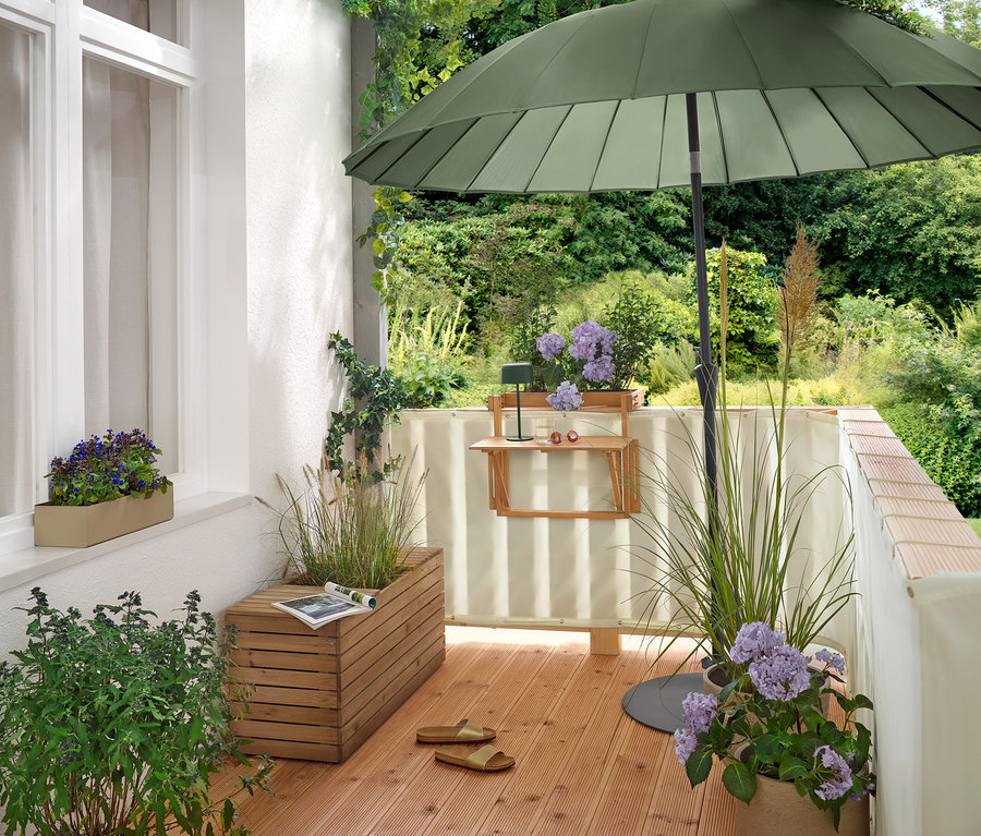 Egy erkélyen egy zöld Leco Shanghai napernyő (Ø 270 cm) áll egy lapos Leco napernyőtalpban (Ø kb. 60 cm).