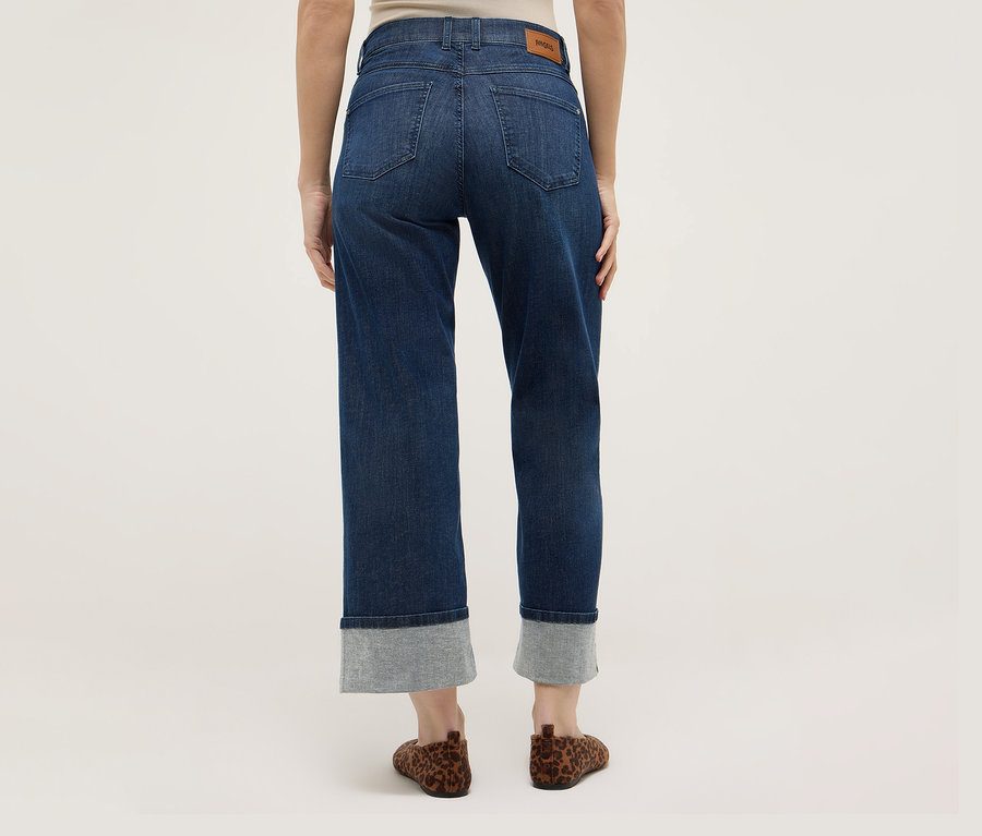 Hátulnézet egy nőről, aki sötétkék Angels Denim »Laia Turn-Up« bőszárú nadrágot és leopárdmintás barna cipőt visel.
