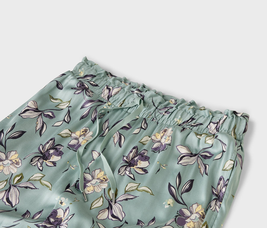 Virágmintás, világoskék nadrág közelről, gumis derékkel és húzózsinórral.