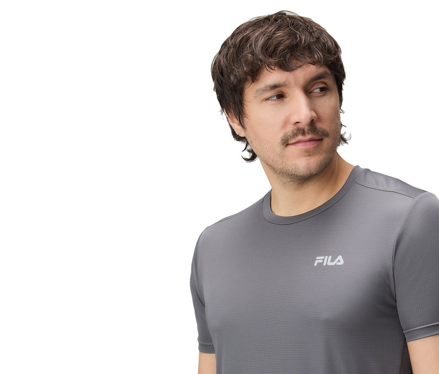 Férfi szürke Fila pólót visel.